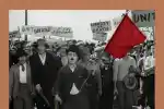Em “Tempos Modernos”, Carlitos corre atrás de um veículo para devolver uma bandeira vermelha e apanha da polícia. Imagem tomada como símbolo